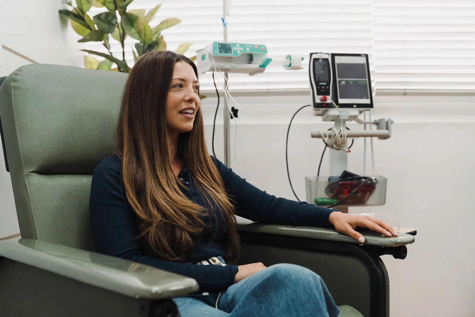 A woman receiving an IV infusion while seated in a recliner in a Celva infusion suite