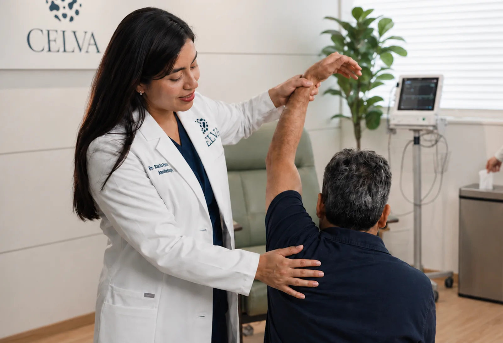 A Celva physician assessing a patient's shoulder during a clinical exam